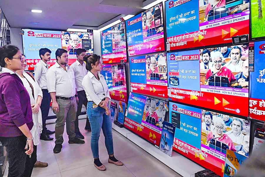 A Photograph shows people watching Budget news in the televisions of an electronics store 