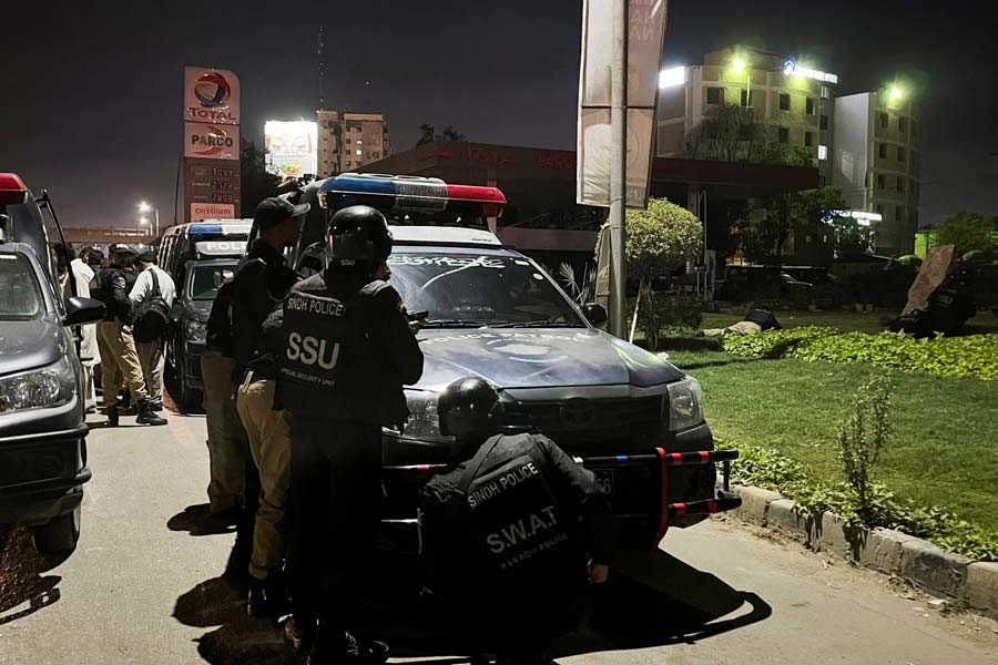 Police officers take position after a police office building was attacked by gunmen in Karachi