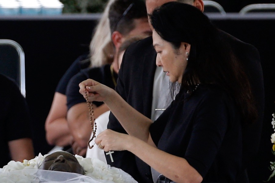 পেলের স্ত্রী মার্সিয়া আয়োকি একটি ক্রুশ পেলের দেহের উপরে রাখছেন।