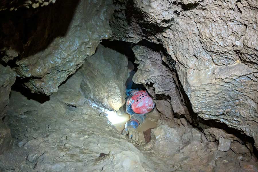 A person trapped in the crevice of rocks trying to get out