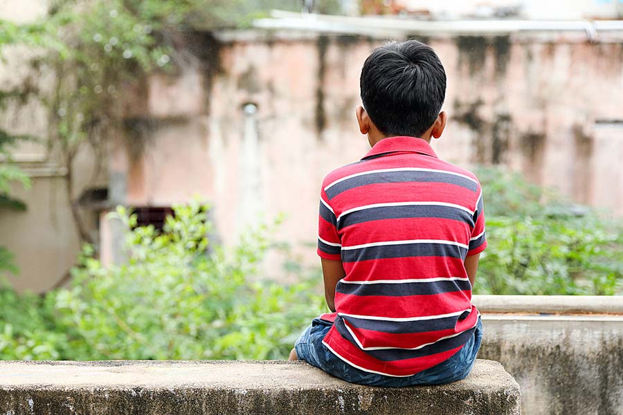 A photograph of a child sitting on a wall