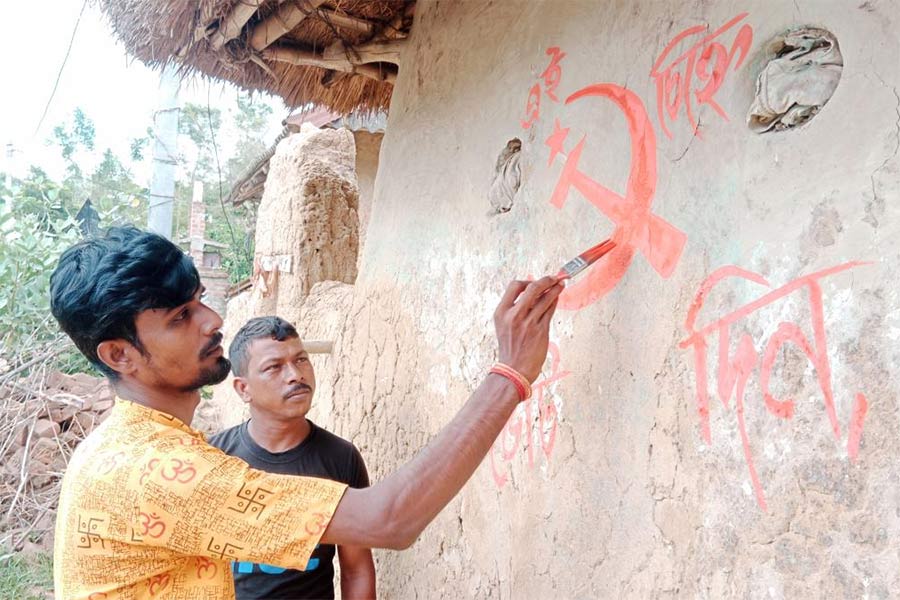 সিপিএমের হয়ে দেওয়াল লিখছেন বিজেপির বুথ সভাপতি। আউশগ্রামে। ছবি: প্রদীপ মুখোপাধ্যায়