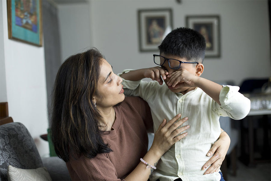 Caring mother comforting her little crying son at home