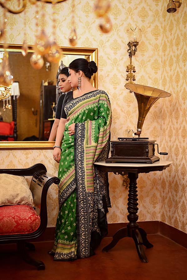 দিনের সাজ যতই লালা সাদাতে সাবেকি হোক না কেন, রাতের সাজ হতে হবে আরও জমকালো। তাই সবুজ তসর শাড়িতে দুই রকম রঙের ডাই করে বানানো জাঁকালো শাড়ি পরাই পোশাক শিল্পী সৈকত বন্দ্যোপাধ্যায়ের পছন্দ। অষ্টমীর শাড়ি বলে কথা, তাই পাড় ও আঁচলে ভারী কাঁথার কাজ থাকলেও পাশাপাশি শাড়ির সারা গা জুড়ে রয়েছে কাঁথার বুটি। 