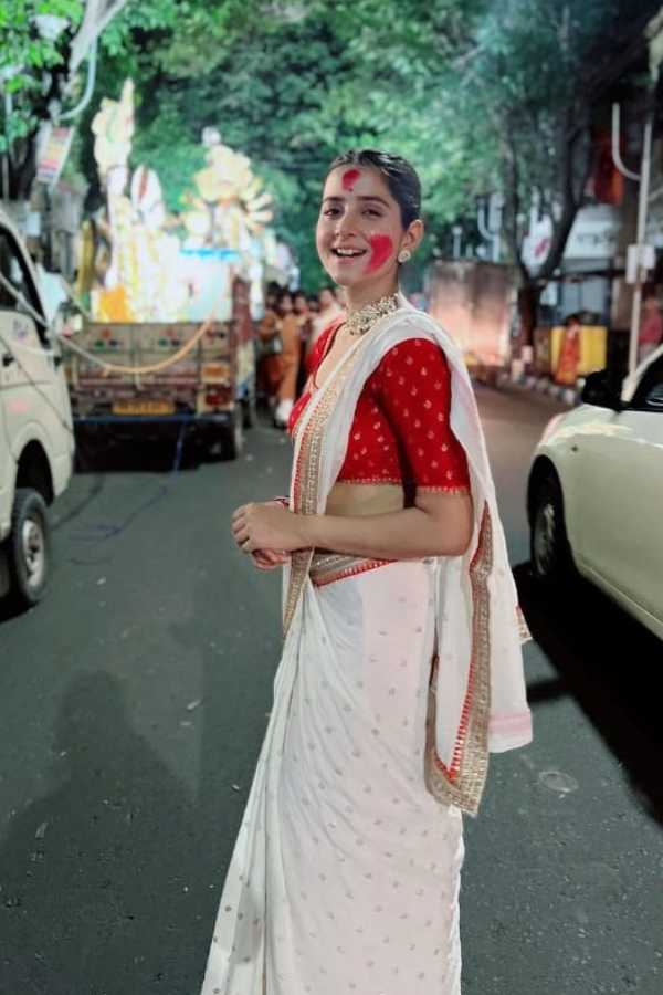 বাংলা টেলিভিশনের জনপ্রিয় অভিনেত্রী দেবচন্দ্রিমাও পিছিয়ে থাকেন নি বিজয়ার আনন্দকে উপভোগ করার থেকে। জরি পাড় সাদা শাড়ির সঙ্গে সোনালি বুটির লাল ব্লাউজে বেশ মানিয়েছিল তাঁকে। প্রসাধহীন মুখের সাজে তাঁর সাজ ছিল স্নিগ্ধ।