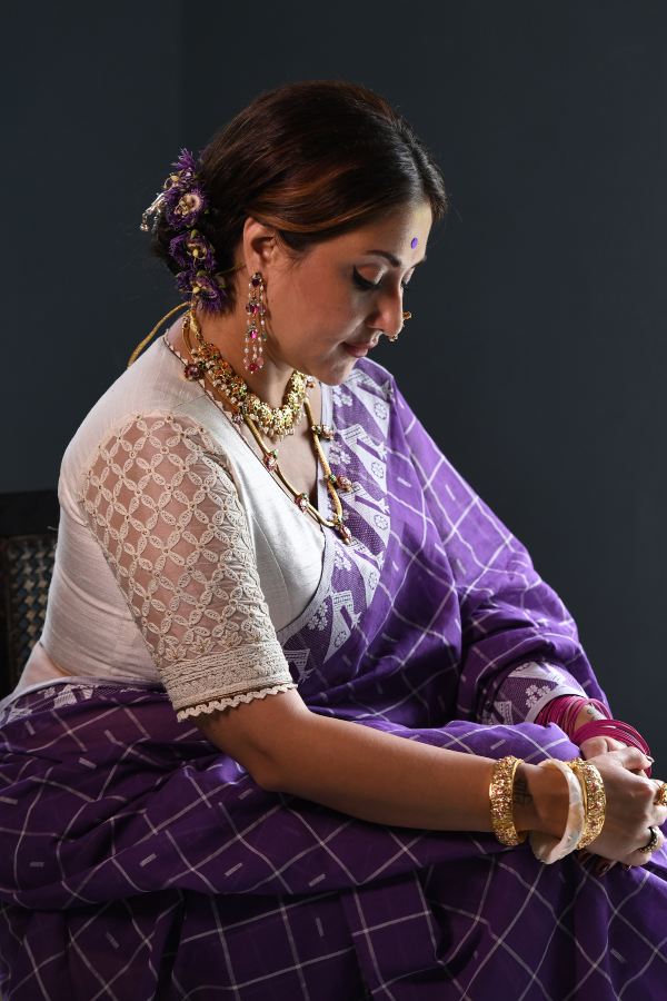 সাদা ব্লাউজে জালের মতো সুতোর কাজ। তার সঙ্গে গায়ে লেপটে থাকা সুতির শাড়ি।চুলের খোঁপায় রয়েছে অপরাজিতা। আনত চোখেও উষ্ণতার ওম। মায়াবন নয়, একলা ঘরে তিনি হরিণী! এবারে চপল নয়। শান্ত, ধীর। অভিজাত। তবু মরীচিকার মতো টানে তাঁর মাধুর্য!  