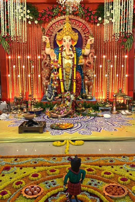  তিনি কিন্তু আর কেউ নন, গণেশের বাহন ইঁদুর। পরনে তাঁর লাল রঙের চেক চেক স্কার্ট এবং সবুজ রঙের ফুল হাতা জামা।   