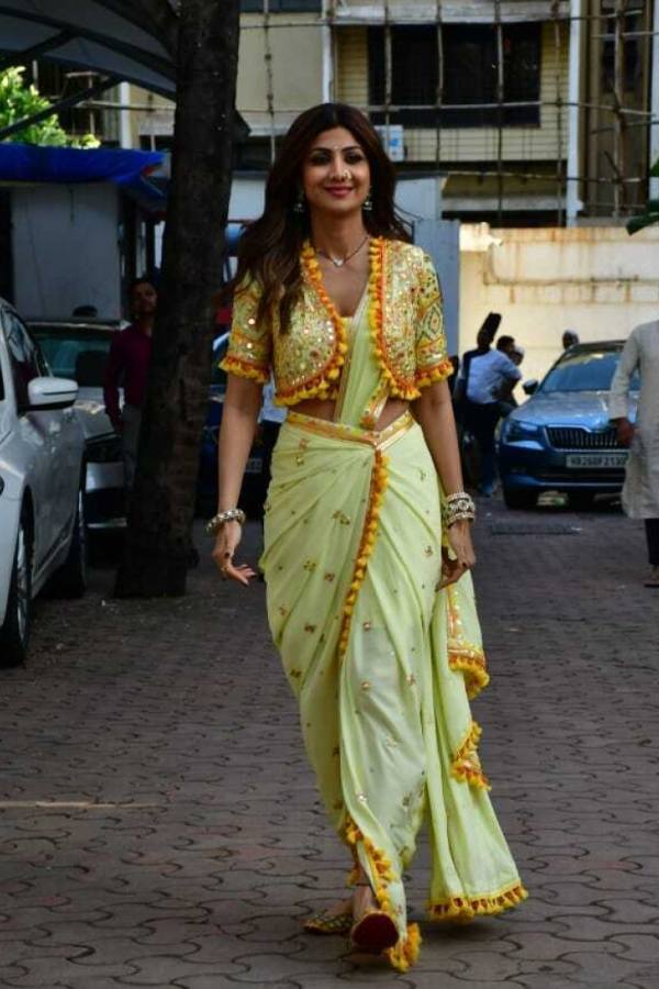 শিল্পা শেট্টি পরেছিলেন একেবারে অন্যরকম এক প্রি-ড্রেপড শাড়ি। ঘিয়ে রঙের শাড়িতে পাড়ে ও বুটিতে ছিল কুসুম হলুদ ও সোনালি জরি পাড়।ব্লাউজের ধরণ ছিল জ্যাকেটের মতো। নাকে মারাঠি ঢঙের নথ ও হাতে সোনালি চুড়ি, এতেই বাজিমাত তাঁর সাজের। 