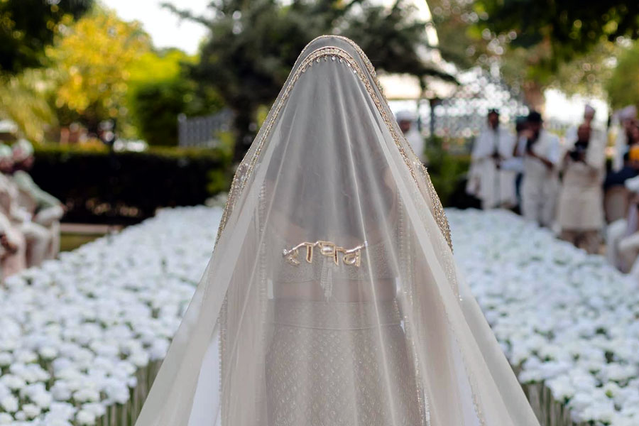 তবে পরিণীতির বিয়ের সাজে বিশেষ ভাবে নজর কাড়ে সোনালি ভেইলের পিছনে দেবনাগরী হরফে লেখা ‘রাঘব’-এর নাম। মণীশ জানিয়েছেন, এই ওড়নার কারুকাজ পুরোটাই হাতে করা। ‘বদলা’ কারুকাজ দিয়ে বোনা হয়েছে রাঘবের নাম।