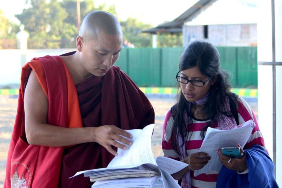 Buddhist monk is studying paper with common people.