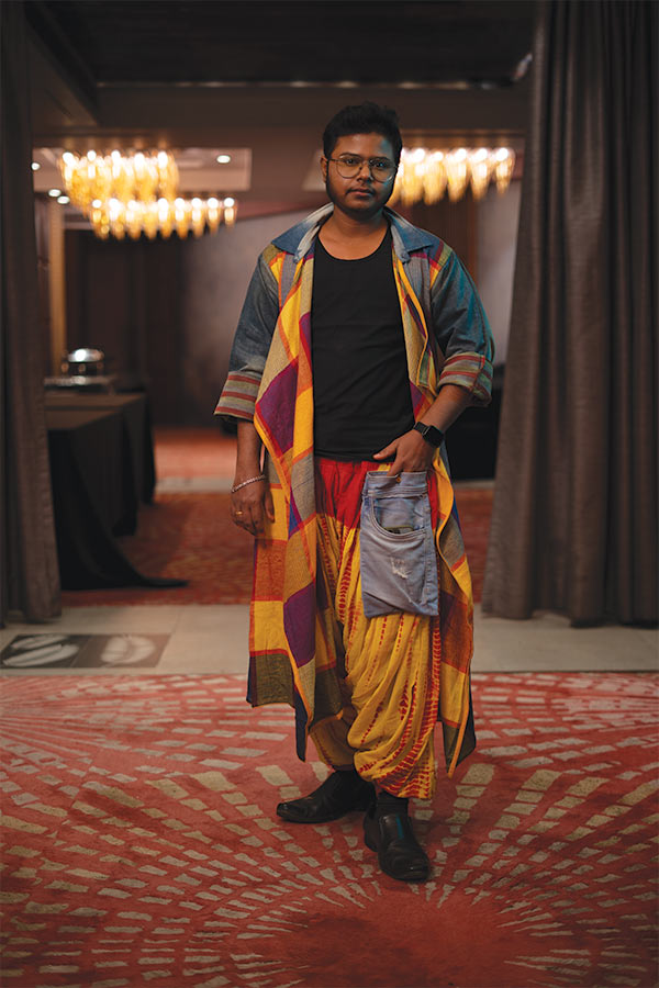 এই দিনেই উপস্থিত ছিলেন ঋষি ঘোষ। রূপান্তরকামী মানুষদের তরফ থেকে তিনি গর্বিত বক্তা। লাজুক হেসে জানালেন বিয়ে করেছেন এর মধ্যেই। পুজোর সাজের জন্য তিনি বেছে নিলেন কালো টিশার্ট, শার্টের আদলে বানানো উজ্জ্বল ও রংবেরঙের শ্রাগ। সঙ্গে লাল-হলুদের বাঁধনি কাজের ধুতি প্যান্ট, তাতে সাম্নের দিকে স্টেটমেন্ট ডেনিম পকেট। 