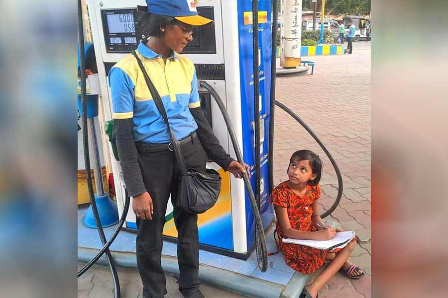 An woman working in petrol pump and her daughter learning beside her
