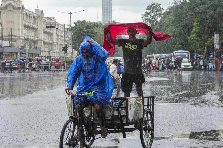 ভারী বৃষ্টিতে মাথা ঢাকার চেষ্টা। বৃহস্পতিবার কলকাতায়।