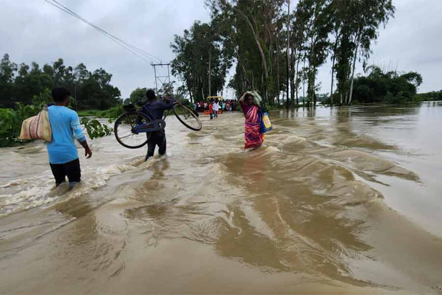 রাস্তায় হাঁটুজল। সাইকেল কাঁধে পার। গোঘাটের কামারপুকুরের সাতবেড়িয়ায়।