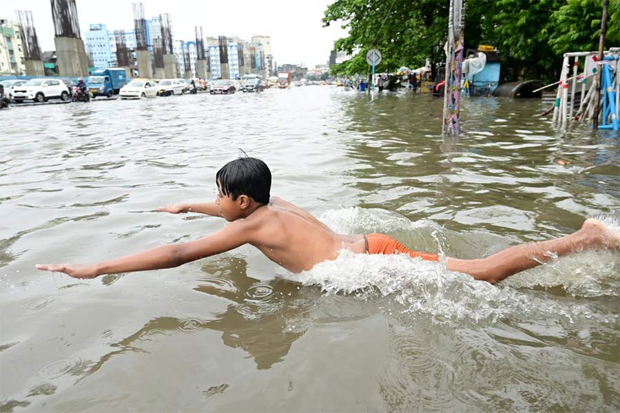 পুকুর নয়, রাস্তার জমা জলেই লাফ-ঝাঁপ এক শিশুর। শনিবার, ভিআইপি রোডের হলদিরামের সামনে।