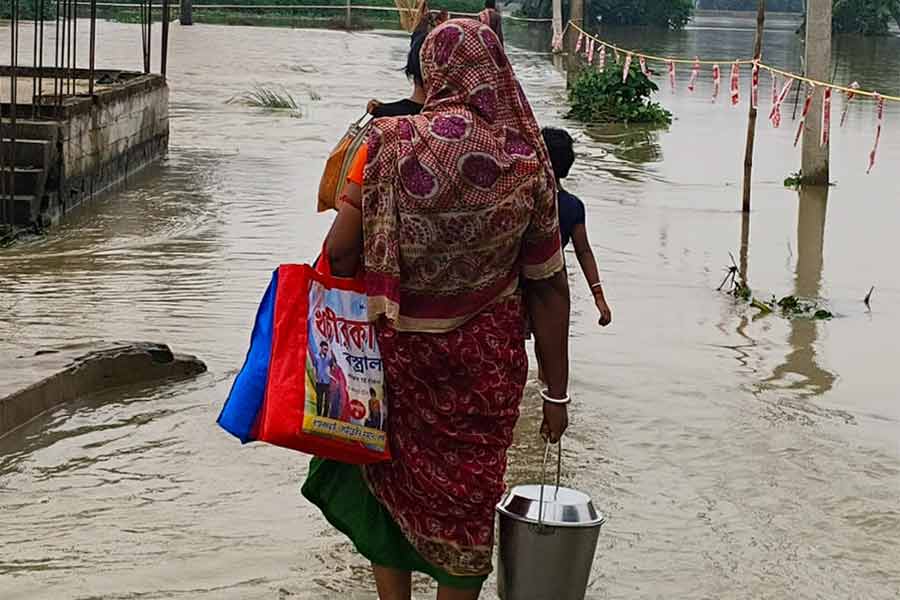 খাবার নিয়ে জল পেরিয়ে বাড়ির পথে। মঙ্গলবার জাঙ্গিপাড়ায়।