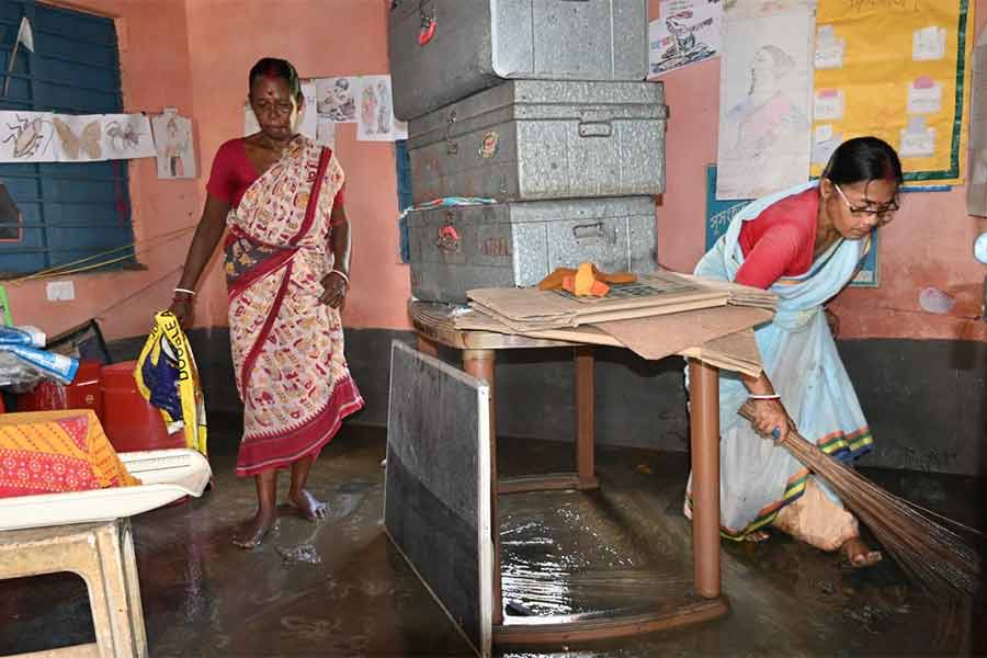 গুসকরায় অঙ্গনওয়াড়ি কেন্দ্রের জমা জল বার করছেন কর্মীরা।