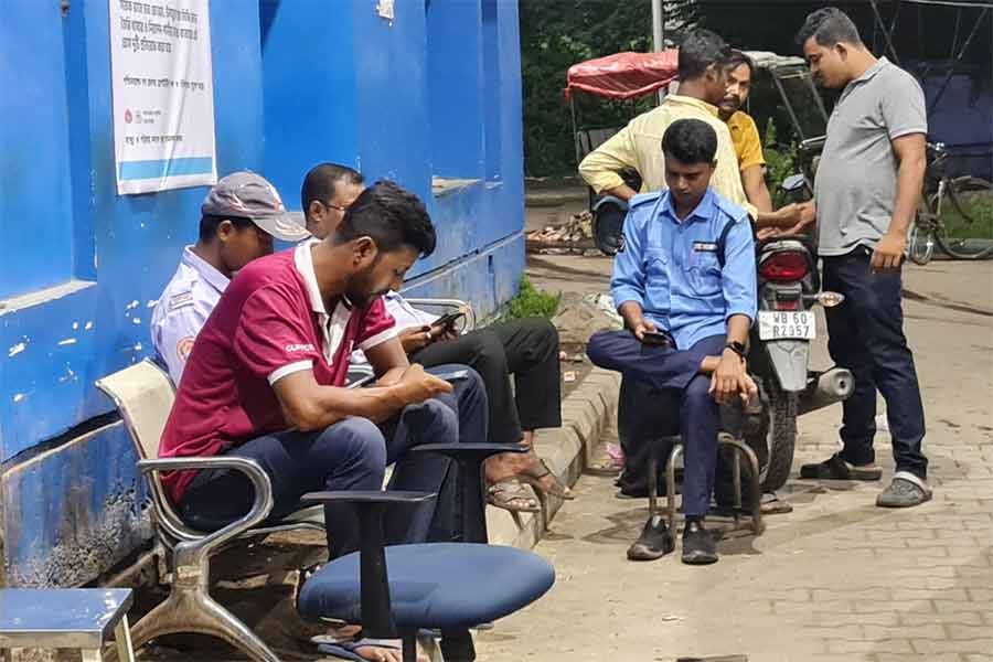 জরুরি বিভাগের বাইরে বসে মোবাইল ফোন দেখছেন রায়গঞ্জ মেডিক্যালে নিরাপত্তার দায়িত্বে কর্মরত সিভিক ভলান্টিয়ার ও