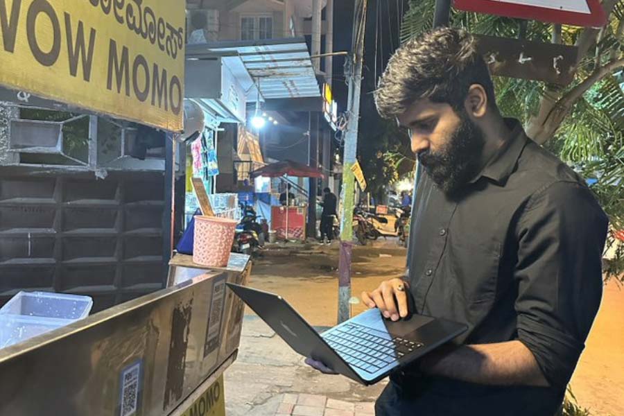 Bengaluru man works on his laptop in front of momo stall