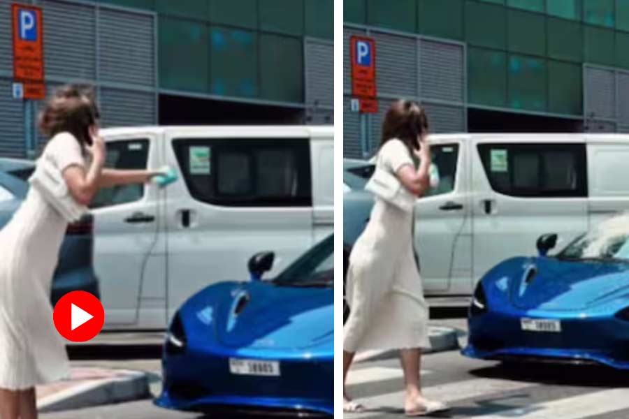 Woman splash coffee on a car in Dubai while crossing road