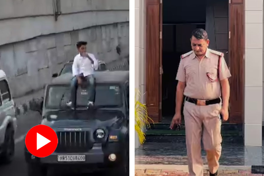 Son of a police sitting on the roof of a moving car on a seemingly busy road