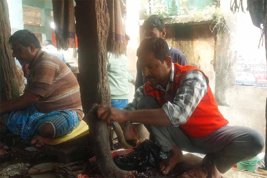 বাজারে মাছ কাটছেন পঞ্চায়েত সদস্য জয়দেব হালদার।