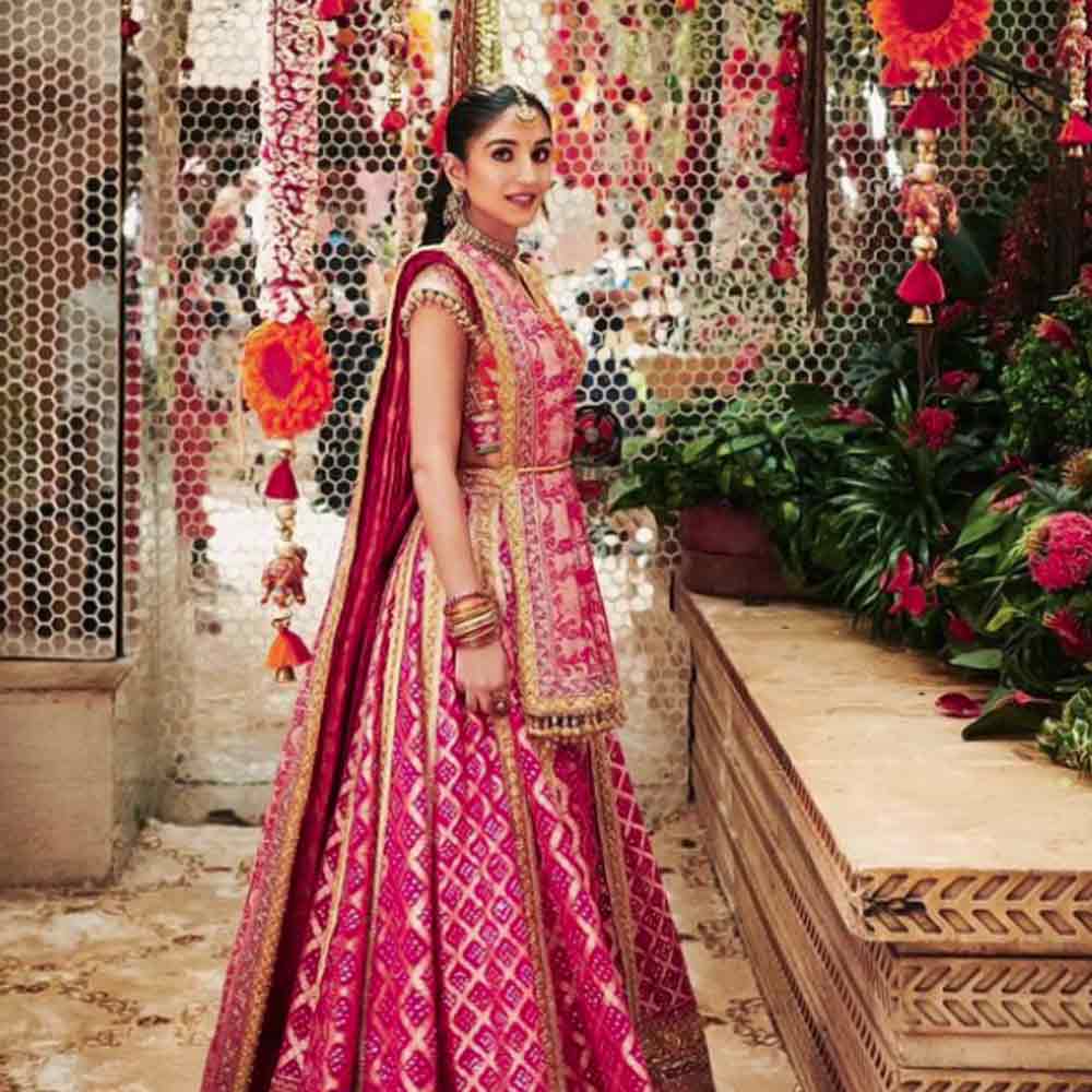 গাঢ় গোলাপি আর কমলার মিশেলের লেহঙ্গায় ঠাসা কাজ। এক ঝলকে দেখলে মনে হবে যেন মণিমুক্তো খচিত। দোপাট্টা-সহ লেহঙ্গায় ঘন জরির কাজ। এ যেন বিয়ের আগেই বৌয়ের সাজ!