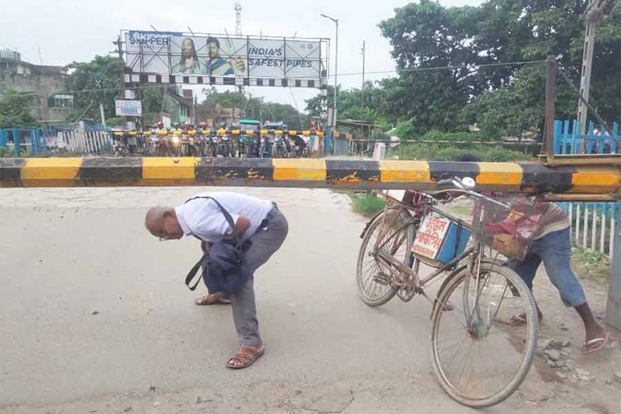 বন্ধ রেলগেট। তবু ঝুঁকি নিয়ে অবাধে পারাপার চলছে। সামসি রেলগেটে। সোমবারের ছবি।