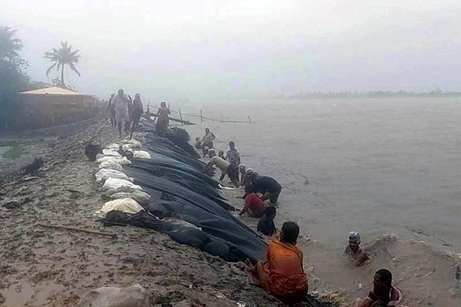 গোসাবায় নদীবাঁধ সারাইয়ের কাজে হাত লাগিয়েছেন গ্রামবাসীরা। —নিজস্ব চিত্র।