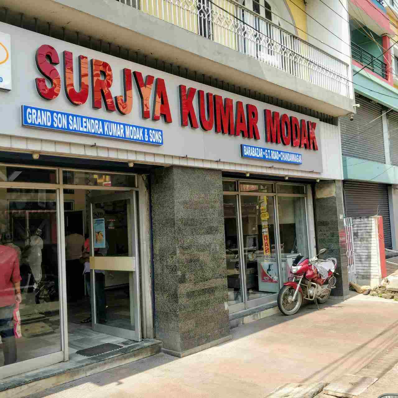 সূর্যকুমার মোদক: চন্দননগর মানে যেমন আলো বোঝায়, ঠিক তেমনই যাঁরা মিষ্টি খেতে ভালবাসেন, তাঁরা জানেন, চন্দননগর মানেই সূর্যকুমার মোদকের বিখ্যাত জলভরা সন্দেশ! প্রায় ২০০ বছর আগে ১৮১৮ সালে ভদ্রেশ্বরের জমিদারের তাঁকে অনুরোধ করেন এমন এক মিষ্টি বানাতে, যা চমকে দেবে তাঁর জামাইদের! 