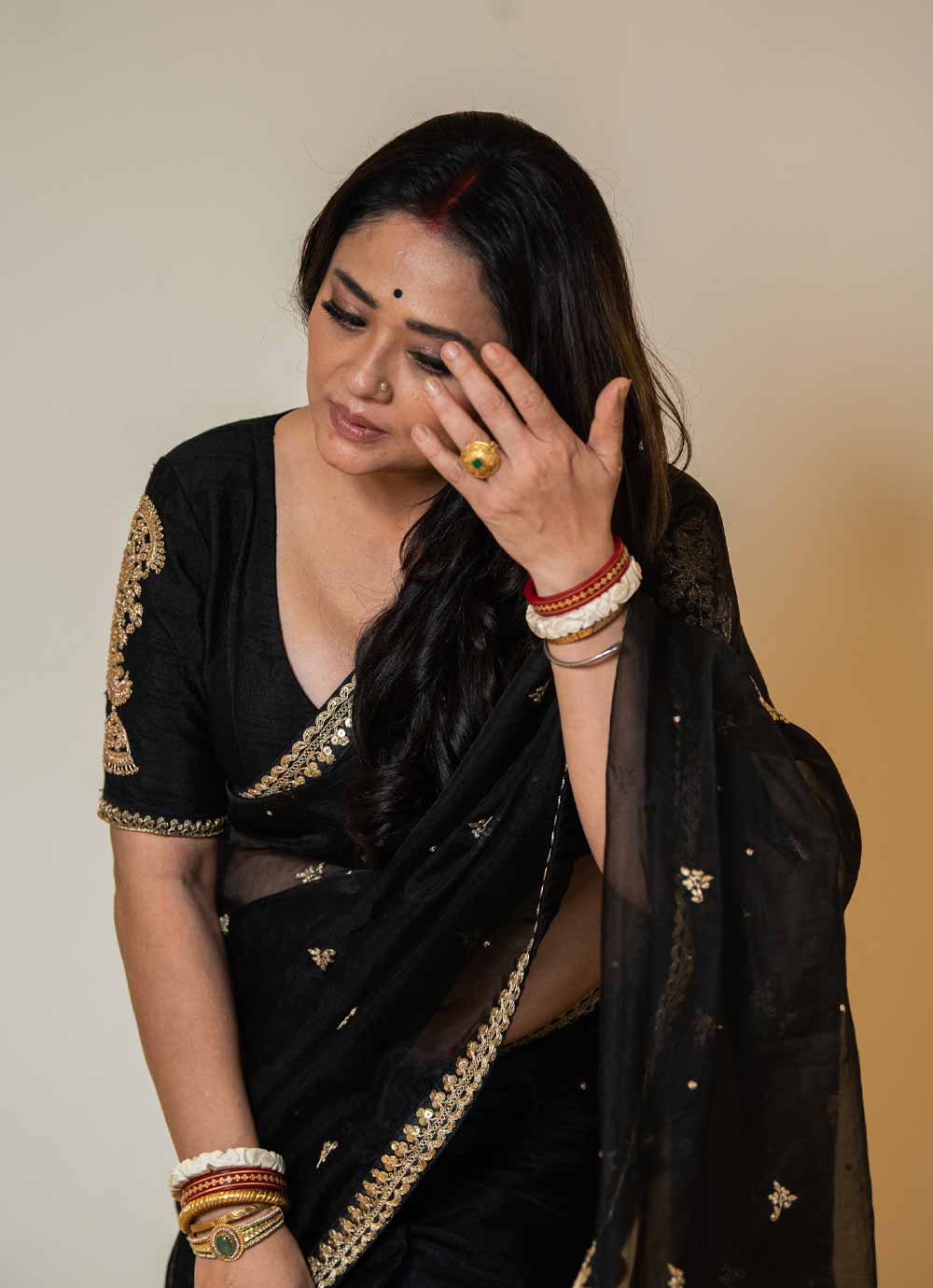 কাঁধের উপর বিনা বাধায় পড়ে থাকা চুলের গোছা, সিঁথিতে সিঁদুরের রেখা, দু’হাতে বিয়ের চিহ্ন শাঁখা-পলার মাঝে উঁকি দিচ্ছে নোয়া, কানে ঝোলা দুল— ব্যস! সপ্তমীর সাজে রূপাঞ্জনার অলঙ্কারের সম্ভার এটুকুই। তবে শাড়িটি বেশ জমকালো। কালো শাড়িতে জরির সরু পাড় আর জরির অসংখ্য মোটিফ সাজগোজে একটা অন্য মাত্রা এনে দিয়েছে। সঙ্গে কালো রঙের ব্লাউজ়টিও বেশ শৌখিন। 