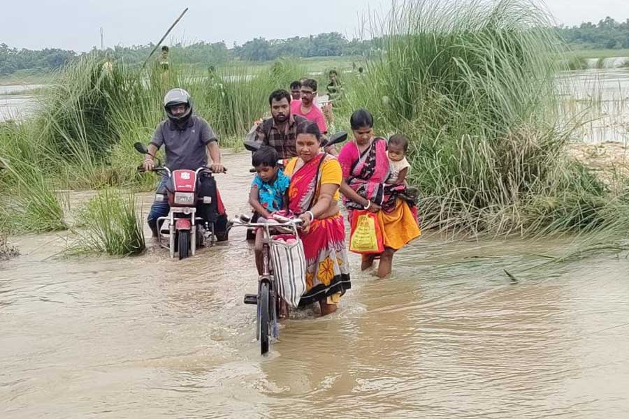 বৃষ্টিতে দামোদরে বেড়েছে জল। নৌকা থেকে নেমে জল পেরিয়ে যাতায়াত।জামালপুরের শম্ভুপুর ঘাটে। ছবি: জয়ন্ত বিশ্বাস