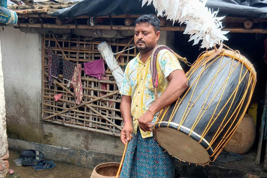 নতুন ঢাক তৈরির পরে বাজিয়ে দেখছেন কালো রুইদাস। সাঁকরাইলের হাওয়াপোতায়। নিজস্ব চিত্র