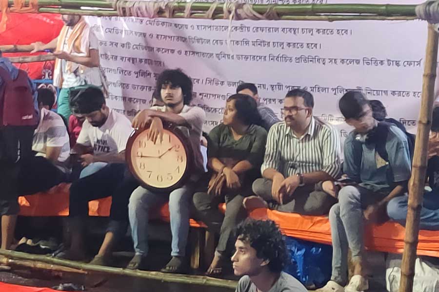 ধর্নামঞ্চে ঘড়ি হাতে নিয়ে বসে এক জুনিয়র ডাক্তার।