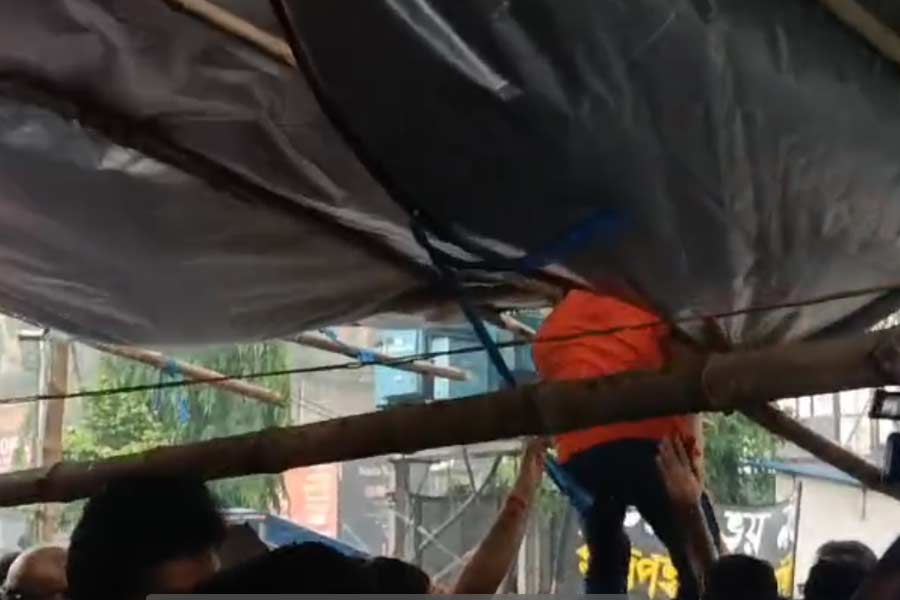 দমকা হাওয়ায় ত্রিপলের একাংশ খুলে গিয়েছিল, বাঁধার কাজে হাত লাগিয়েছেন জুনিয়র ডাক্তারেরা। রবিবার ধর্মতলায়।