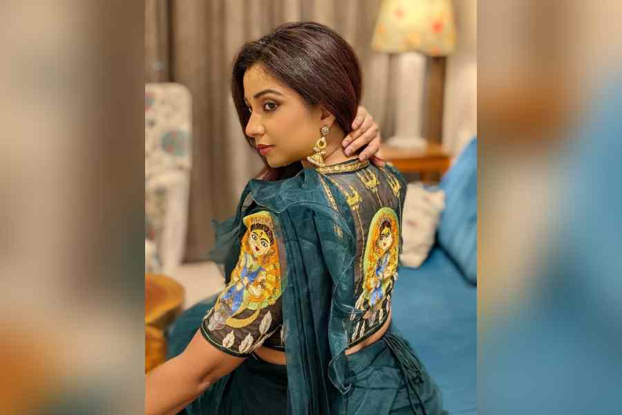 পরনে নীল রঙের অভিনব শাড়ি, কোমরে জড়ানো বেল্ট। সেখানে আবার সোনালি জরির কাজে উজ্জ্বল ভাবে লেখা 'বলো দুর্গা মাইকি জয়'! সেই সঙ্গে নজর কাড়ল শ্রেয়া ঘোষালের পরনের ব্লাউজও। পিঠে এবং হাতে আঁকা দুর্গা মায়ের ছবি। ছবি পোস্ট করে শারদীয়ার শুভেচ্ছা জানাতে ভুললেন না গায়িকা। 