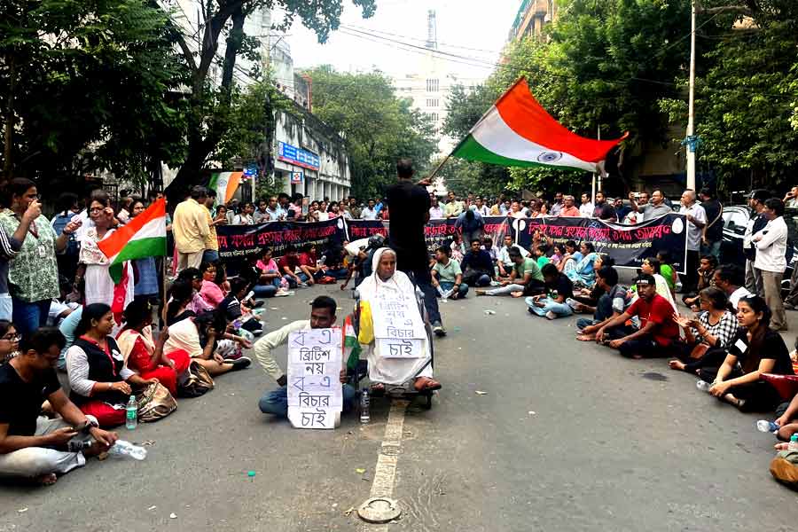 সোমবার বিকেলে রাজভবনের সামনের রাস্তায় বসে রয়েছেন মিছিলে অংশগ্রহণকারীরা।