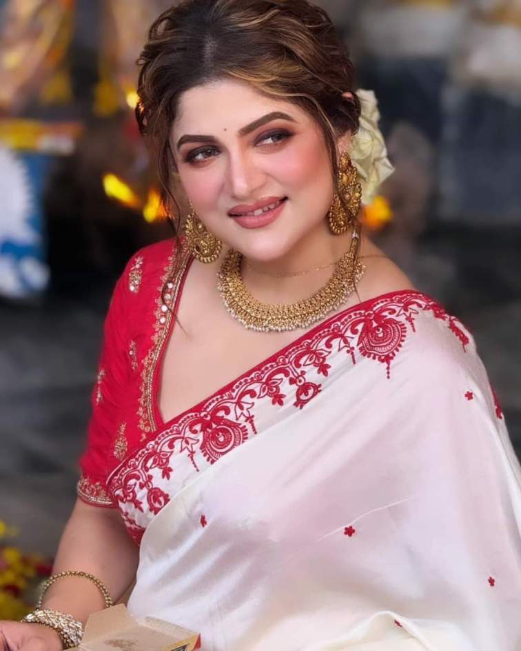 বিকেল গড়িয়ে তখন সন্ধে, গোটা পুজো মণ্ডপের অপেক্ষা তখন একজনকে ঘিরেই। কিছু মুহূর্তের অপেক্ষা, তারপরেই পুজো প্রাঙ্গনে এসে হাজির হন শ্রাবন্তী চট্টোপাধ্যায়। পরনে লাল পাড় সাদা রঙের শাড়ি, খোঁপায় ফুল আর ঠোঁটে সেই চেনা হাসি। 