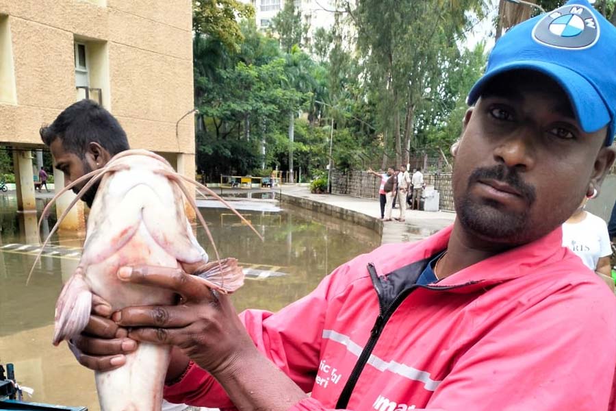 Resident of an apartment complex holding a fish in hand amid the waterlogging