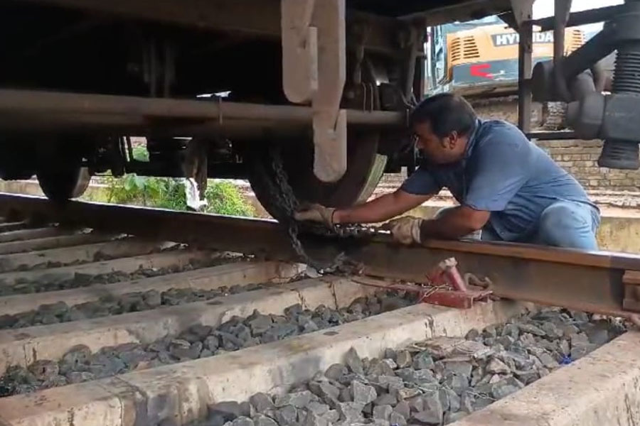 ট্রেনের চাকায় শিকল পড়াছেন রেলকর্মী।