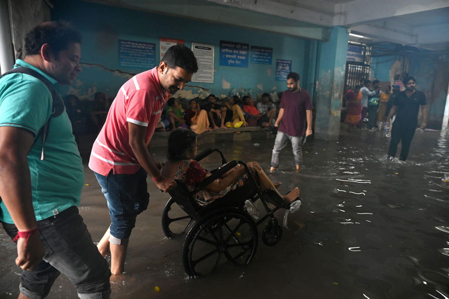 নাস্তানাবুদ: ভারী বৃষ্টিতে জলমগ্ন এসএসকেএম হাসপাতাল। তার মধ্যে দিয়েই হুইলচেয়ারে বসিয়ে কোনওক্রমে নিয়ে যাওয়া হচ্ছে এক রোগীকে। শুক্রবার।