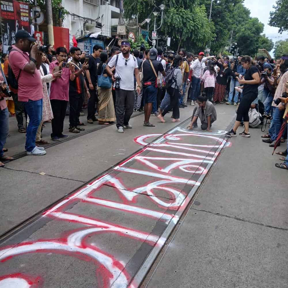 মিছিল শুরু হওয়ার আগে রাস্তার উপরে লেখা হচ্ছে ‘আমরা তিলোত্তমা’।