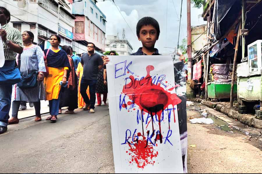 পোস্টার হাতে দাঁড়িয়ে রয়েছে এক শিশু। পোস্টারে লাল রঙের ছিটেফোঁটা।
