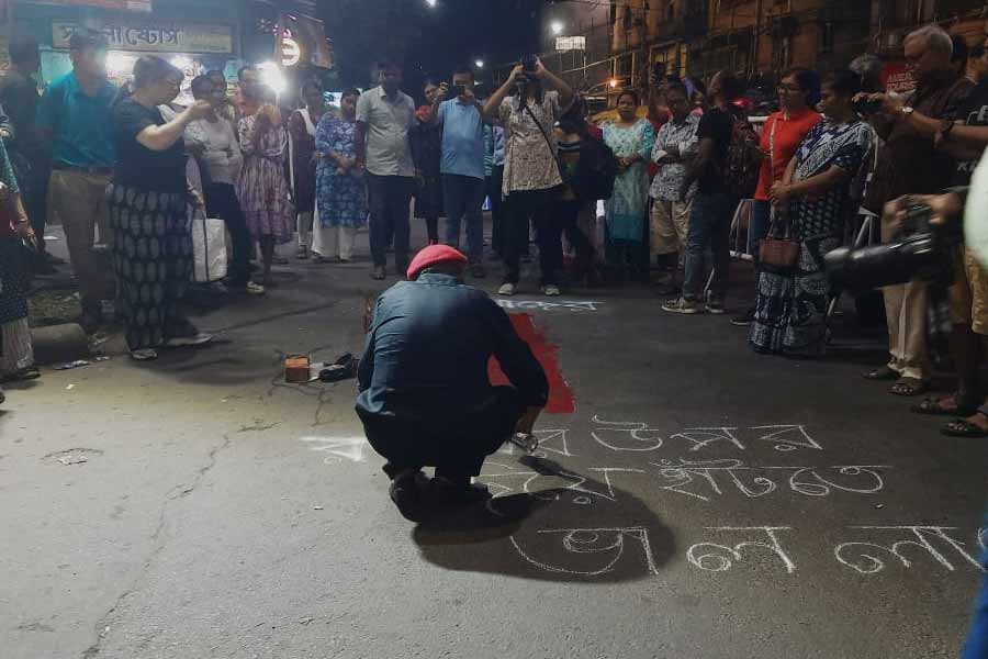 রাস্তায় স্লোগান লিখছেন প্রতিবাদীরা।