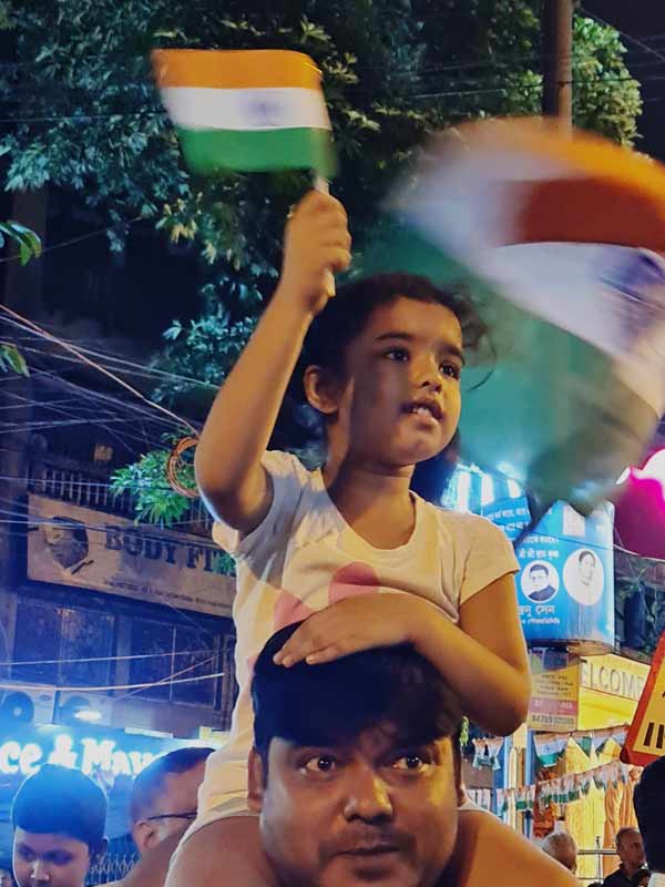 বাবার পিঠে চেপে রাতদখলে খুদে। রবিবার সিঁথির মোড়ে। 