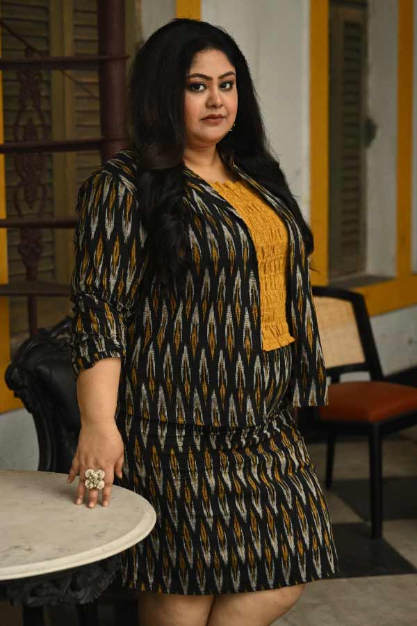 “আমি কখন কোথায় যাব, কেমন পোশাক পরব— তার কৈফিয়ৎ দিতে বাধ্য নই”, সাফ কথা অভিনেত্রী সঙ্ঘশ্রী সিংহের। তাঁর কোমর থেকে কালো ইক্কতের স্কার্ট ঝুলছে হাঁটু পর্যন্ত। একই কাপড়ে তৈরি সুতির জ্যাকেট আর সর্ষে-রঙা টিউব টপে সঙ্ঘশ্রীর প্রতিবাদী সত্তাই ফুটে উঠছে। অভিনেত্রীর খোলা চুল আর জ্বলন্ত দৃষ্টি যেন স্লোগান তোলে—‘না মানে, না’। পোশাক ভাবনার সঙ্গে মানানসই একটি ব়ড় আংটি সঙ্ঘশ্রী পরেছেন হাতের মধ্যমায়।  সঙ্ঘশ্রী বলেন, “বডি শেমিং, কালার শেমিং, এজ শেমিং নিয়েই তো আমরা বেঁচে আছি। আমার খুব ইচ্ছে করে হাতা কাটা জামা পরতে, পারি না। বন্ধুরা বলে, হাত না গদা!” সে সব কিছু দূরে ঠেলে সঙ্ঘশ্রী চান নিজের মতো করে বাঁচতে। 