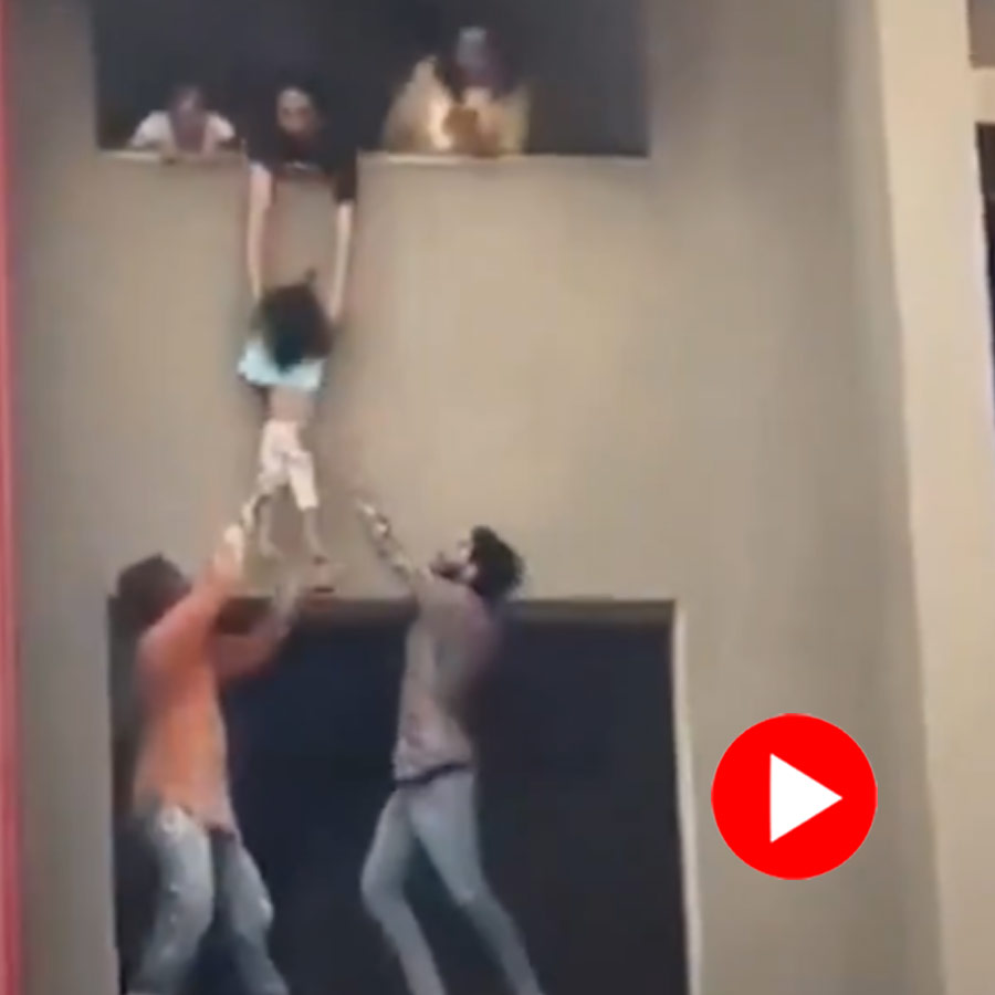 A woman can be seen dangling one child in the air