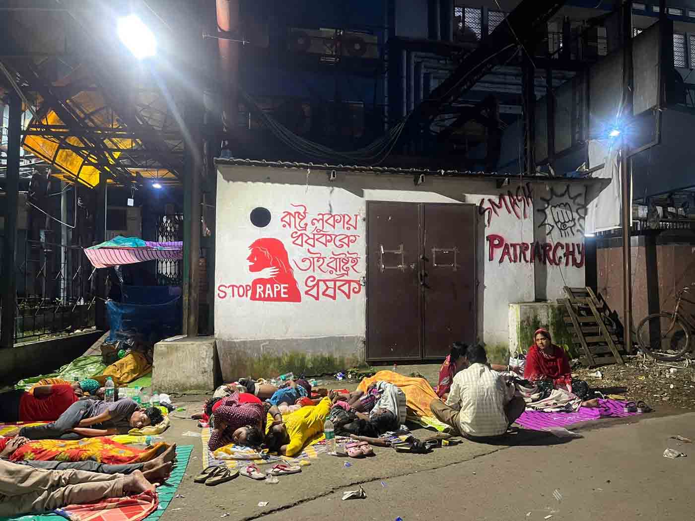 আরজি কর হাসপাতালের জরুরি বিভাগের নীচে শুয়ে রোগীর পরিজনেরা। শুক্রবার রাতে। —নিজস্ব চিত্র।