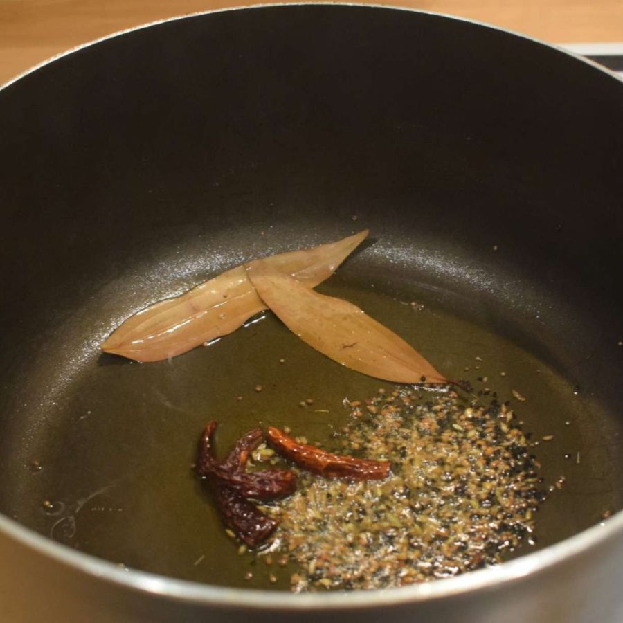 ৮। এর পরে একটা কড়াইতে সামান্য তেল দিয়ে তাতে দিয়ে দিন তেজপাতা, গোটা তিন-চারেক শুকনো লঙ্কা, জিরে এবং আদা বাটা। 