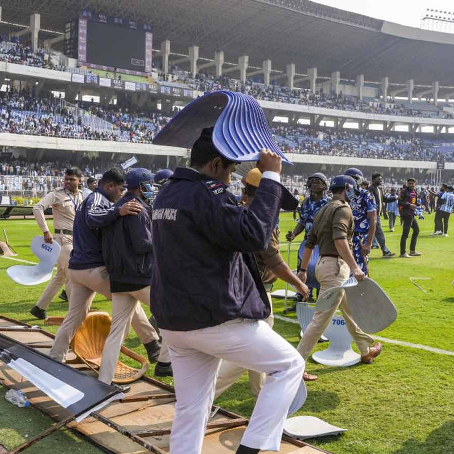 মাথা বাঁচাতে দর্শকদের ভাঙা চেয়ার ঢাল করেছেন এক পুলিশকর্মী। শনিবার যুবভারতীতে।